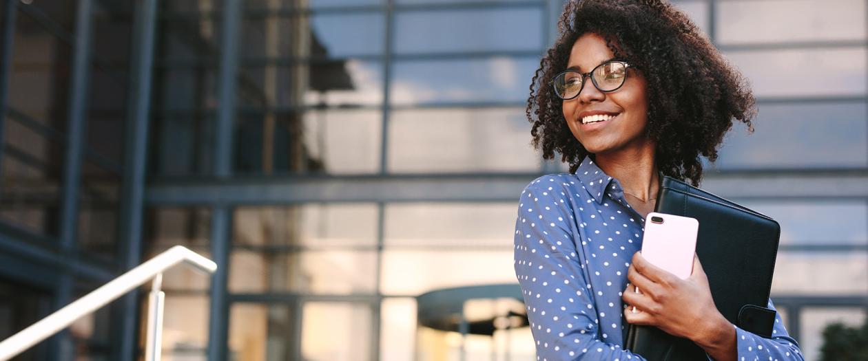 smiling woman with glasses holding portfolio and phone